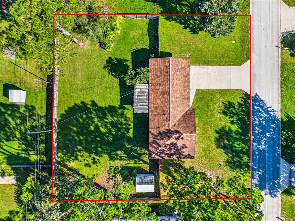 An aerial view shows a house with a brown roof, a driveway, and a fenced yard — 2530 NORDMAN AVENUE, NEW SMYRNA BEACH, FL