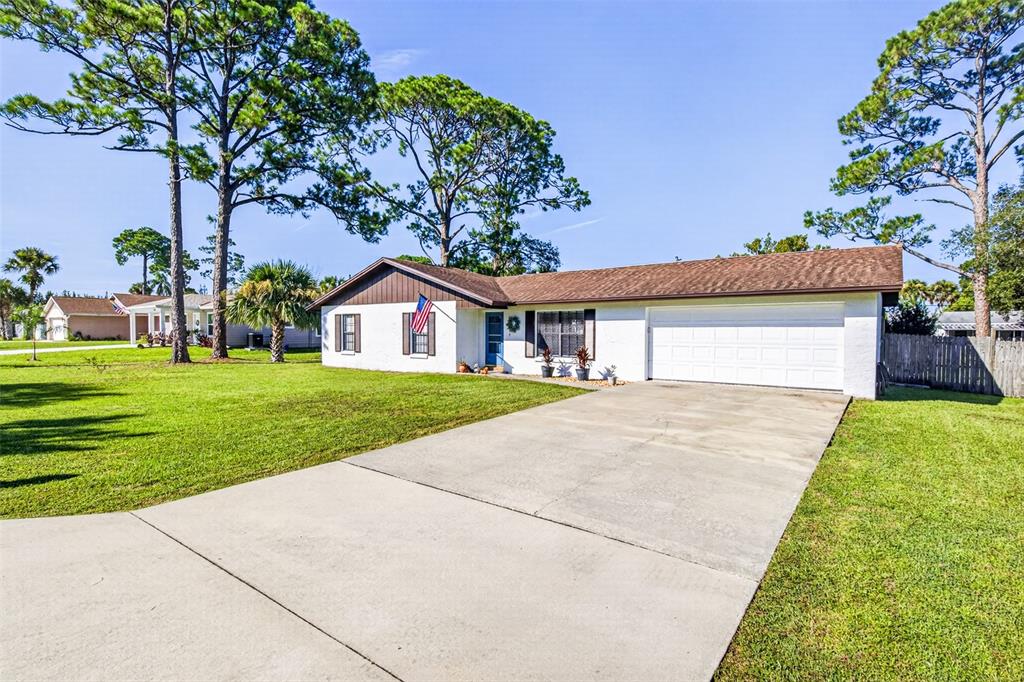 A single-story white house with a brown roof and a concrete driveway sits on grass — 2530 NORDMAN AVENUE, NEW SMYRNA BEACH, FL
