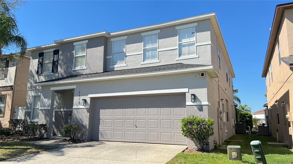 A two-story suburban house with a gray stucco exterior and a two-car garage — 1113 PINE RIDGE DRIVE, DAVENPORT, FL
