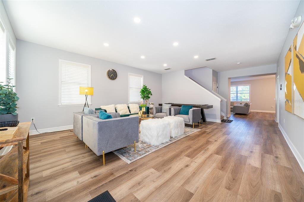 A living room features light wood flooring, gray upholstered furniture, and a staircase — 1113 PINE RIDGE DRIVE, DAVENPORT, FL