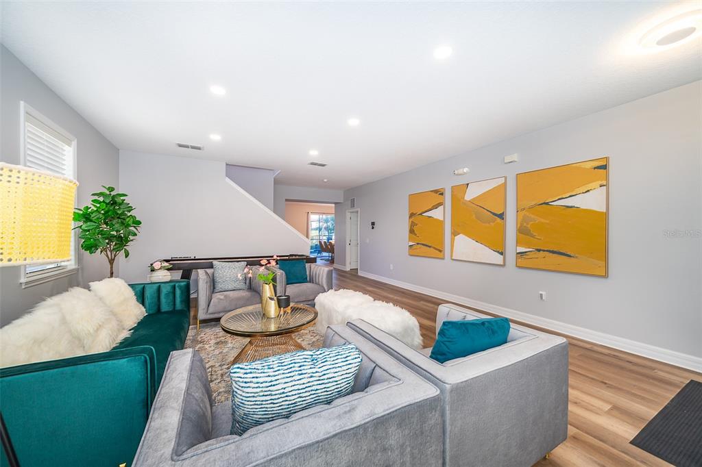 A living room features a green sofa, gray armchairs, a coffee table, and abstract wall art — 1113 PINE RIDGE DRIVE, DAVENPORT, FL