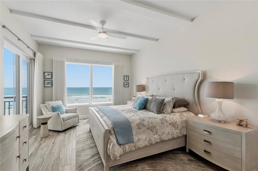 A bedroom features a bed with a wooden frame, a gray bench, and plantation shutters — 807 S ATLANTIC AVENUE UNIT 303, NEW SMYRNA BEACH, FL