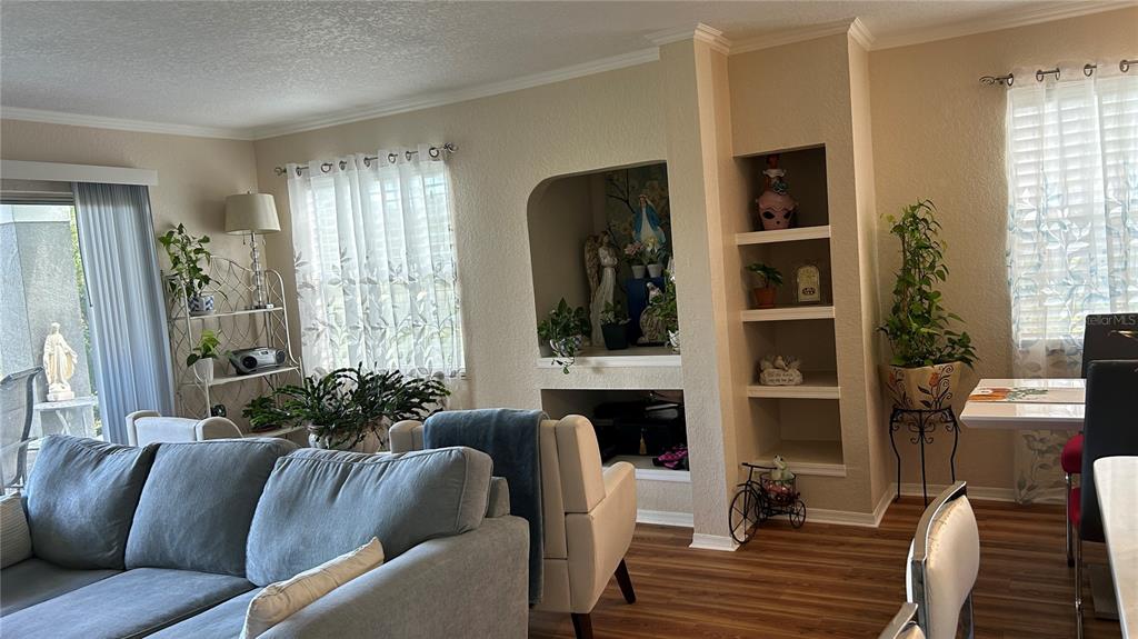 A living room features a gray sofa, built-in shelving, and a dining area with wood flooring — 14037 FAIRWAY ISLAND DRIVE UNIT 218, ORLANDO, FL