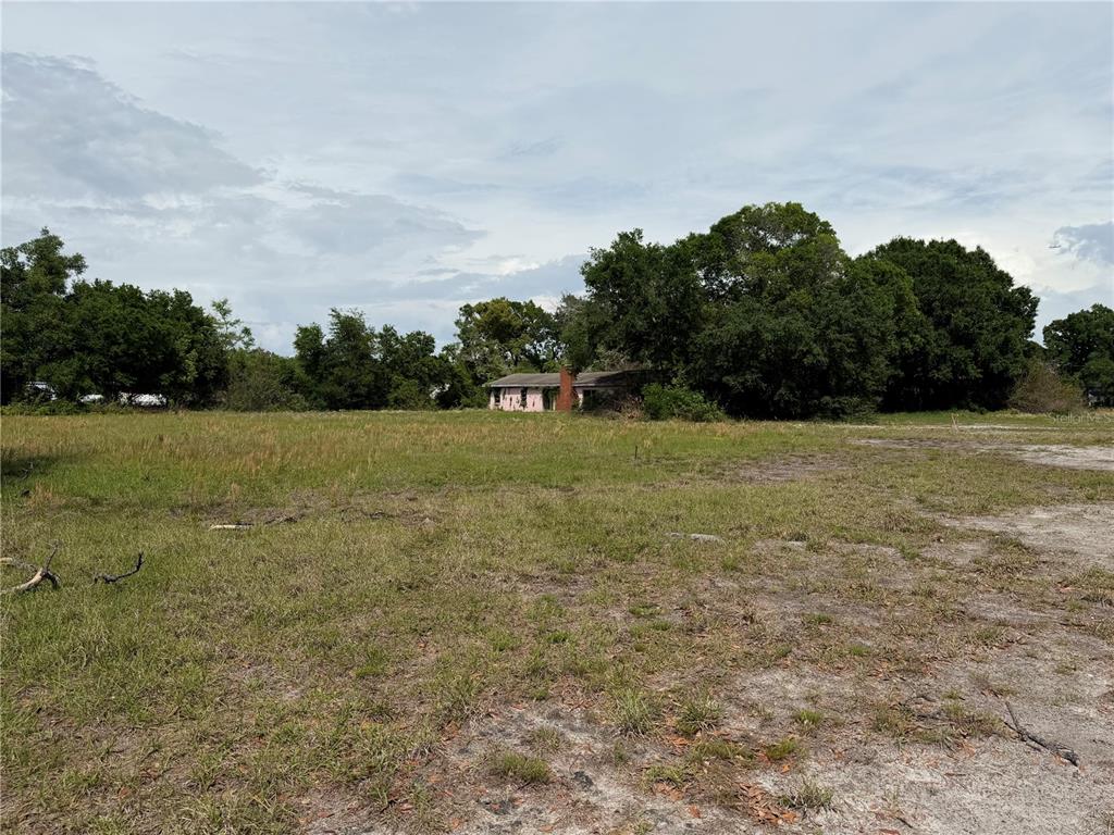 A small, weathered house with a brick chimney sits in the middle of a grassy field — 4075 OLD CANOE CREEK ROAD, ST CLOUD, FL