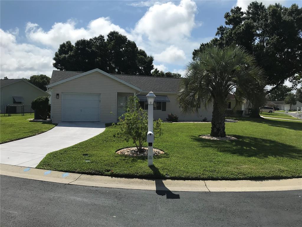 A single-story house with light siding, a garage, a palm tree, and a front lawn — 11879 SW 137TH LOOP, DUNNELLON, FL