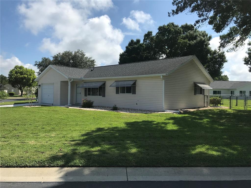 A single-story house with light-colored siding, a garage, and metal window awnings — 11879 SW 137TH LOOP, DUNNELLON, FL