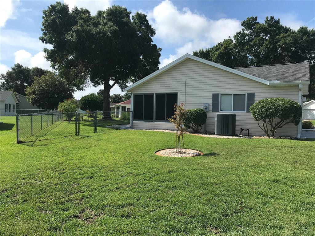 A beige house with a screened-in porch and a fenced backyard under a blue sky — 11879 SW 137TH LOOP, DUNNELLON, FL