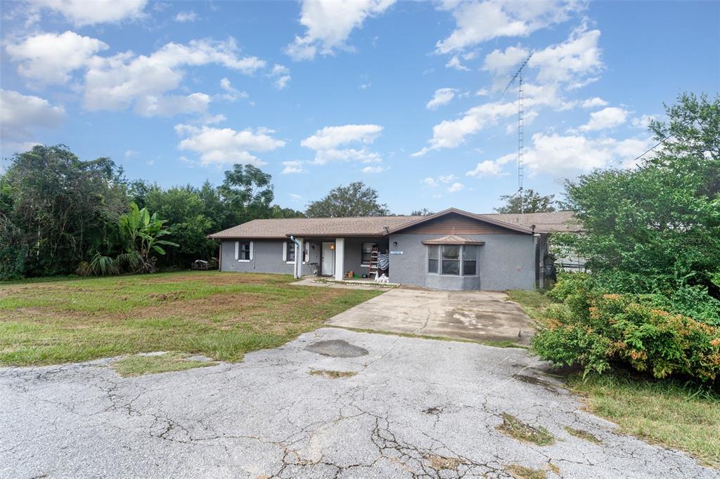 A single-story gray house with a concrete driveway and a large antenna in the yard — 13678 SE 51ST AVENUE, SUMMERFIELD, FL