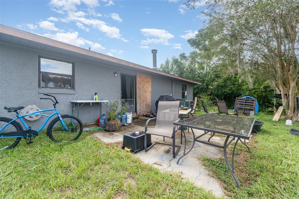 A backyard view of a gray house exterior with a patio, furniture, and a bicycle — 13678 SE 51ST AVENUE, SUMMERFIELD, FL