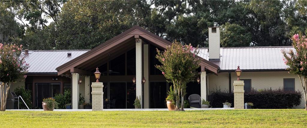 A single-story house with a large gabled porch, brick columns, and a metal roof — 12870 W HIGHWAY 40, OCALA, FL