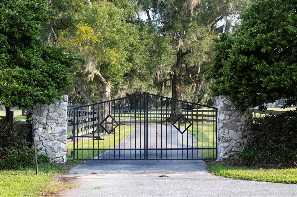 A black metal gate sits between two stone pillars at the entrance to a driveway — 12870 W HIGHWAY 40, OCALA, FL