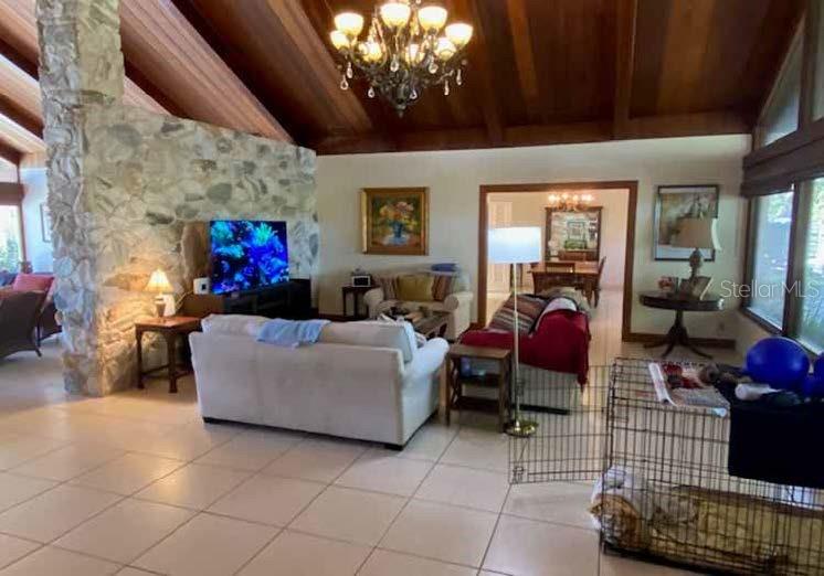 A living room features a stone fireplace, vaulted wood ceilings, and tile flooring — 12870 W HIGHWAY 40, OCALA, FL