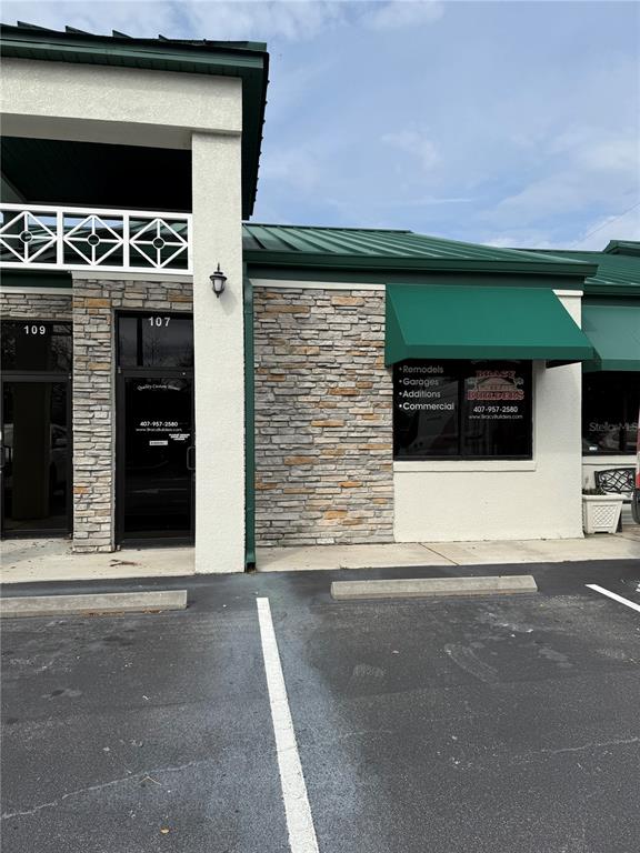 The exterior of a commercial building features stone veneer, green metal roofing, and glass doors — 107 E 13TH STREET, ST CLOUD, FL