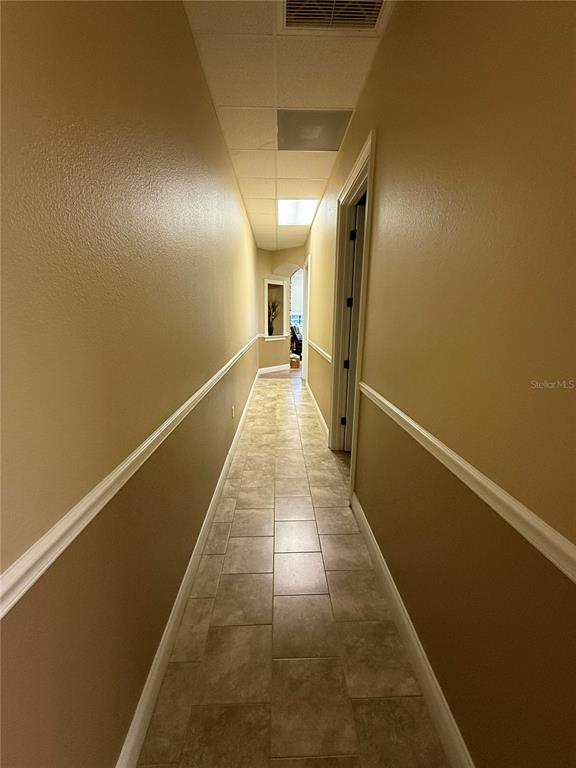 A narrow hallway features tan walls with white chair rail molding and tiled flooring — 107 E 13TH STREET, ST CLOUD, FL
