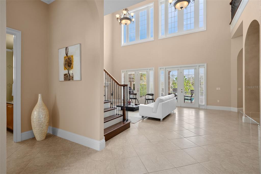 A spacious foyer with tile floors, a staircase, and a view into a bright living area — 490 MUIRFIELD LOOP, REUNION, FL