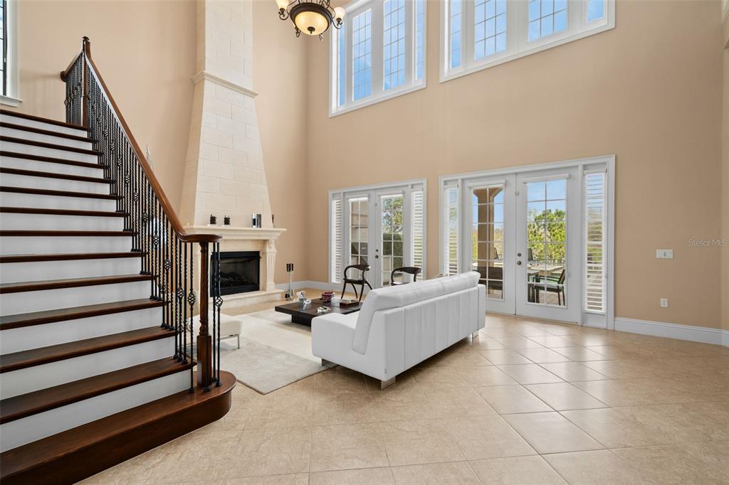 A living room with a tall fireplace, a staircase, and a white sofa on tile floors — 490 MUIRFIELD LOOP, REUNION, FL