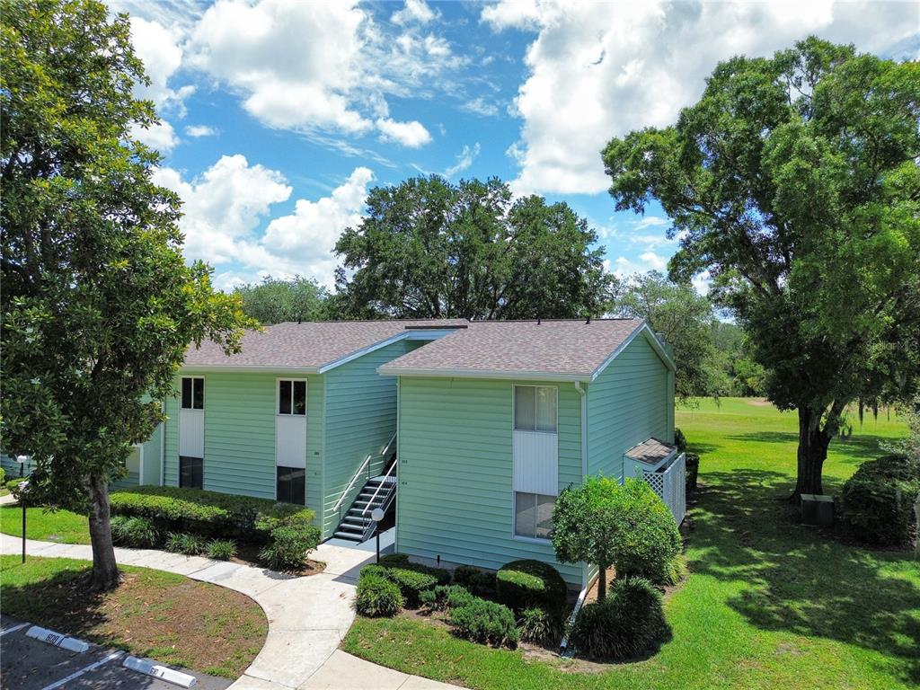 An exterior view of a two-story, light green apartment building with a staircase and landscaping — 608 MIDWAY DRIVE UNIT A, OCALA, FL