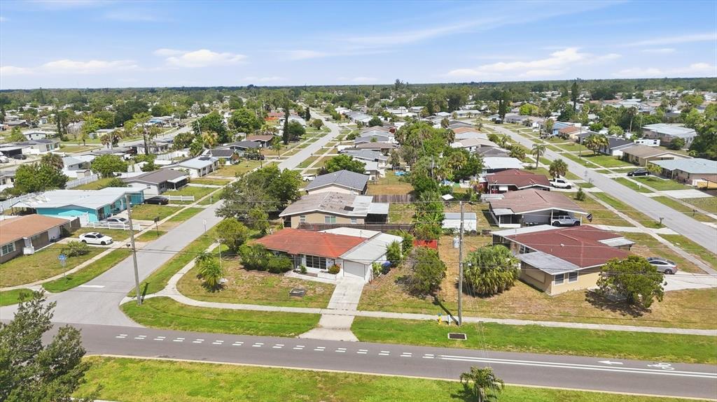 An aerial view shows a suburban neighborhood with single-story homes, paved streets, and green lawns — 4751 S BISCAYNE DRIVE, NORTH PORT, FL