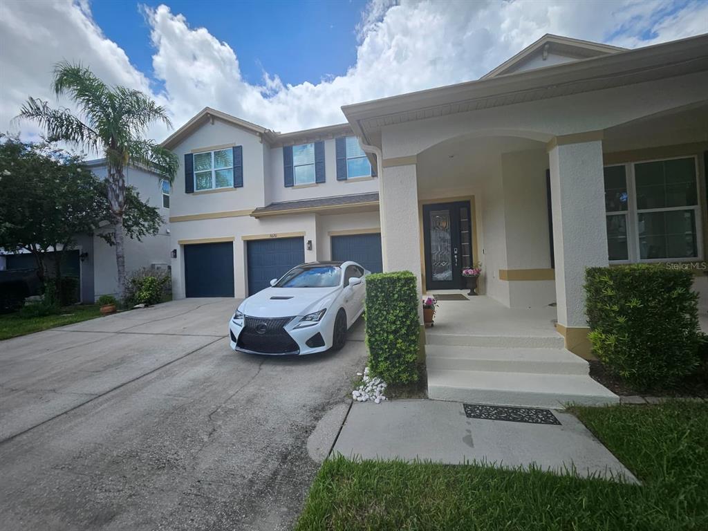 A white two-story house with a three-car garage and a white car parked in front — 5620 MANGROVE COVE AVENUE, WINTER GARDEN, FL