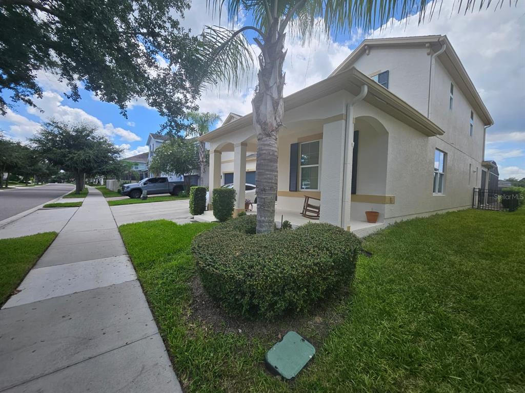 A two-story suburban house features a front porch, a palm tree, and a manicured lawn — 5620 MANGROVE COVE AVENUE, WINTER GARDEN, FL