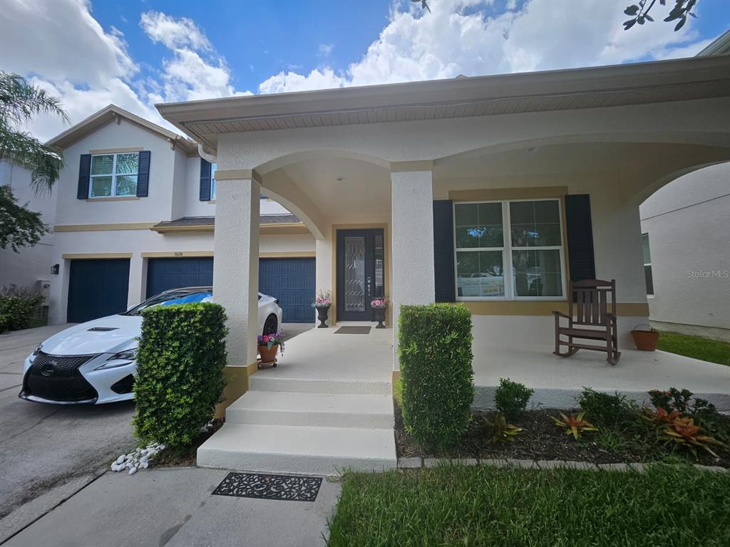 A white house with a covered front porch, dark shutters, and a parked white car — 5620 MANGROVE COVE AVENUE, WINTER GARDEN, FL