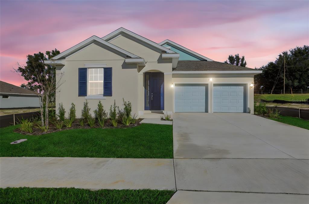 A single-story house with a two-car garage, blue shutters, and a front lawn at dusk — 5295 SPADERDOCK LANE, APOPKA, FL