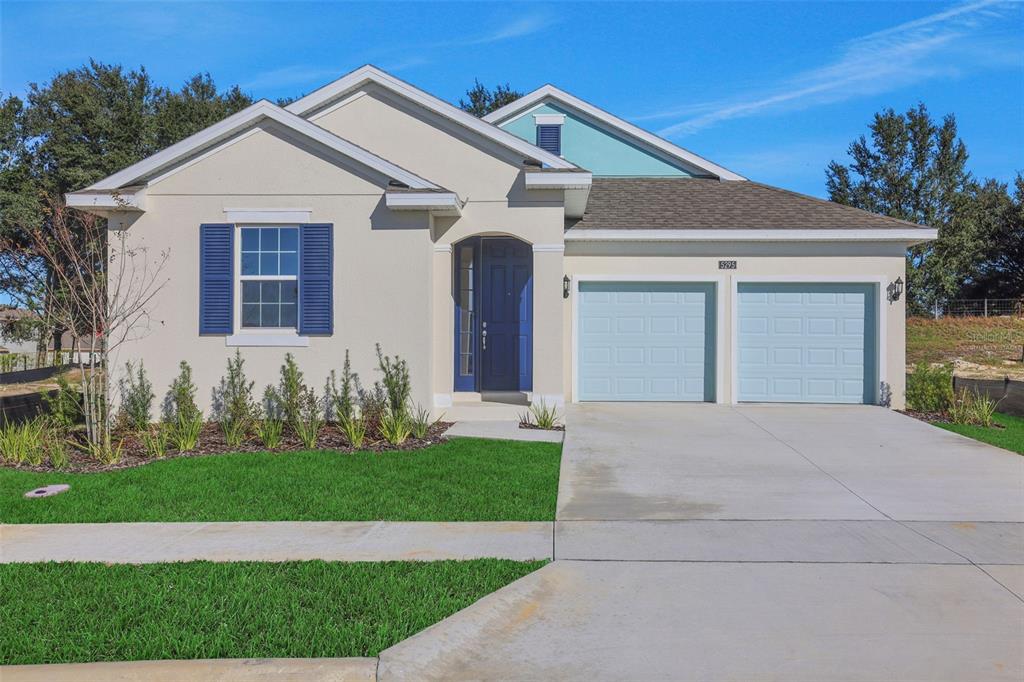 A single-story house with a beige stucco exterior, blue shutters, and a two-car garage — 5295 SPADERDOCK LANE, APOPKA, FL
