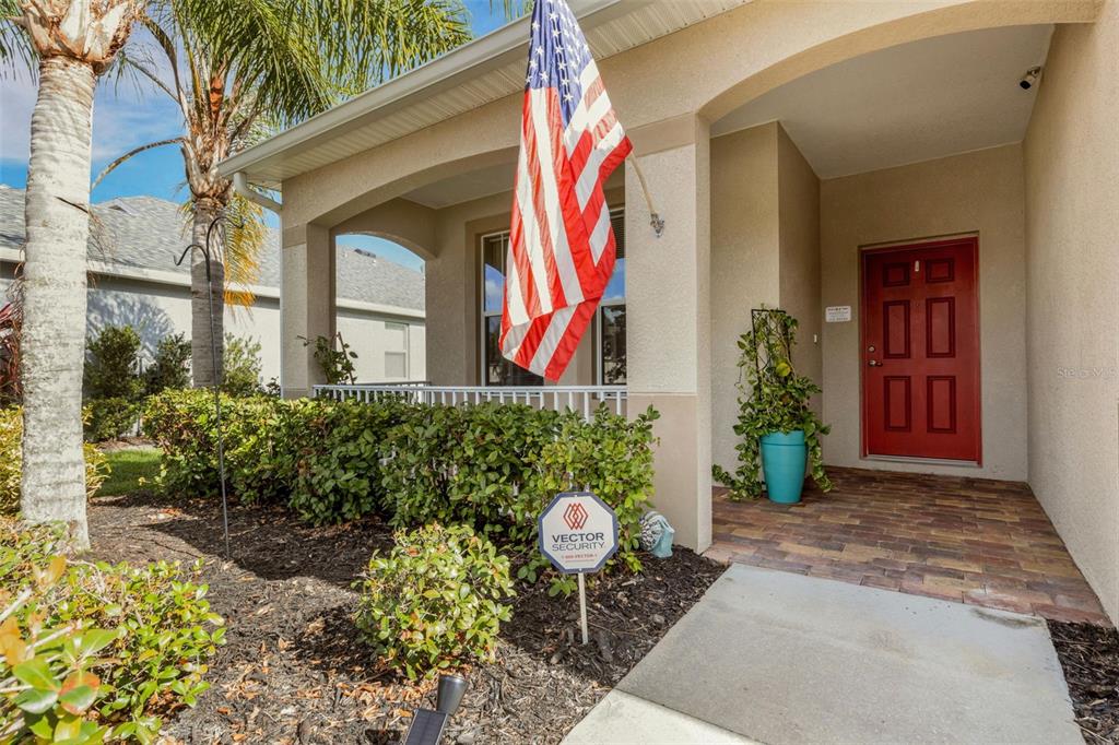 A front entryway features a red door, a porch with a railing, and an American flag — 5220 119TH TERRACE E, PARRISH, FL