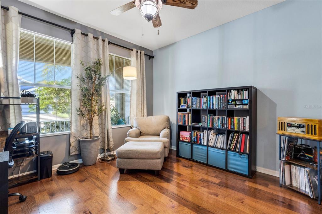 A home office features hardwood floors, a bookshelf, an armchair with ottoman, and two windows — 5220 119TH TERRACE E, PARRISH, FL