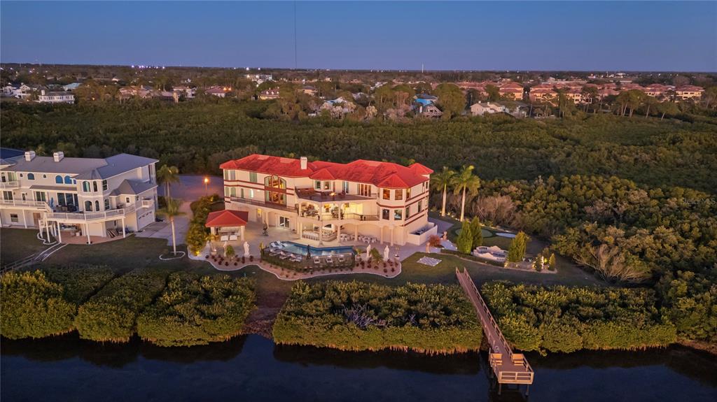 An aerial view of a large waterfront house with a red roof, pool, and dock — 2115 ALEXIS COURT, TARPON SPRINGS, FL