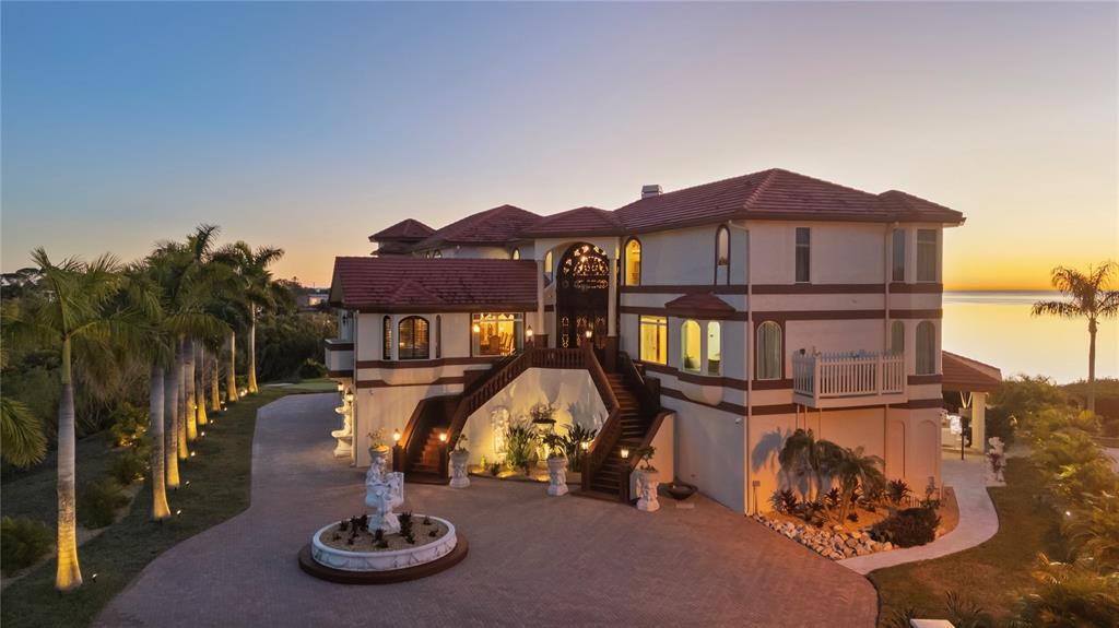 A large multi-story house with a red tile roof, grand staircase, and circular driveway — 2115 ALEXIS COURT, TARPON SPRINGS, FL