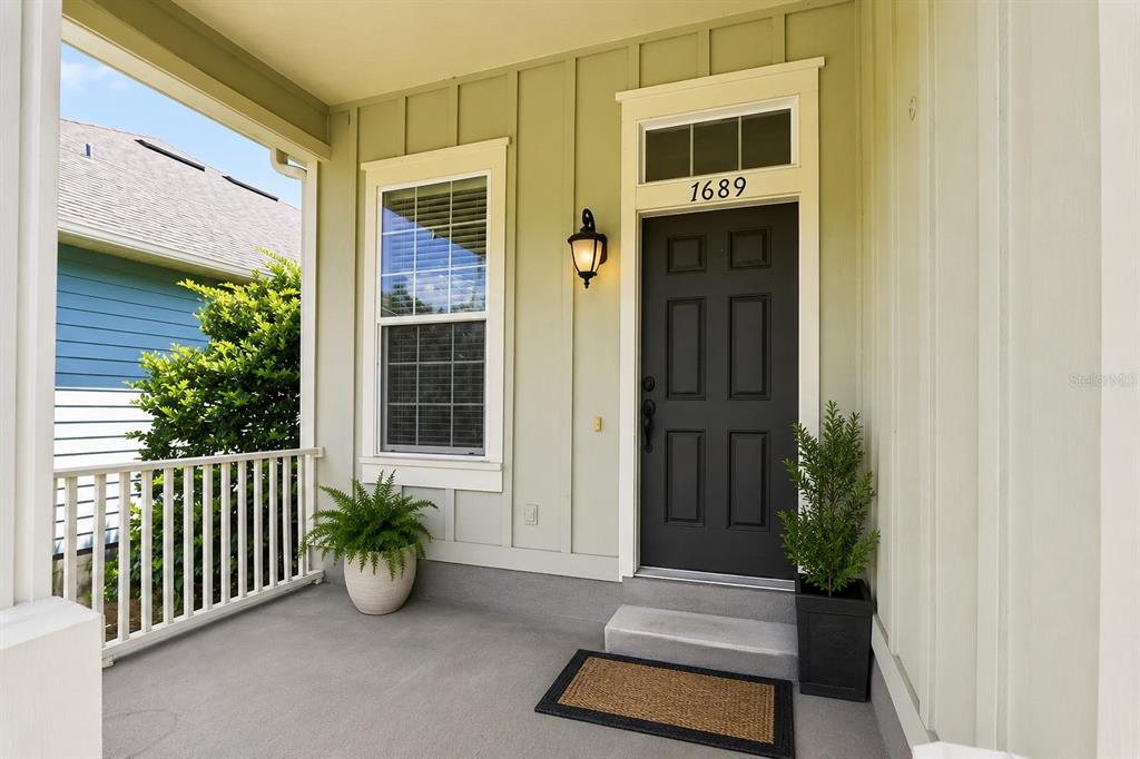 A covered front porch features a dark door, a window, and two potted plants — 7689 SW 24TH LANE, GAINESVILLE, FL