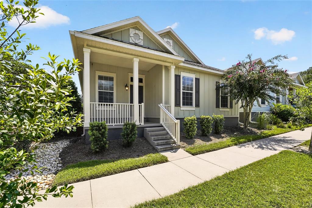 A light green house with a front porch, white railings, and a concrete walkway — 7689 SW 24TH LANE, GAINESVILLE, FL