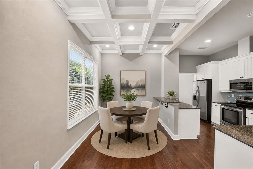 A dining area with a coffered ceiling, round table, and chairs next to a kitchen — 7689 SW 24TH LANE, GAINESVILLE, FL