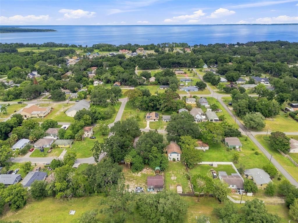 An aerial view shows a residential neighborhood with scattered houses surrounded by trees near water — 320 W SADLER AVENUE, OAKLAND, FL