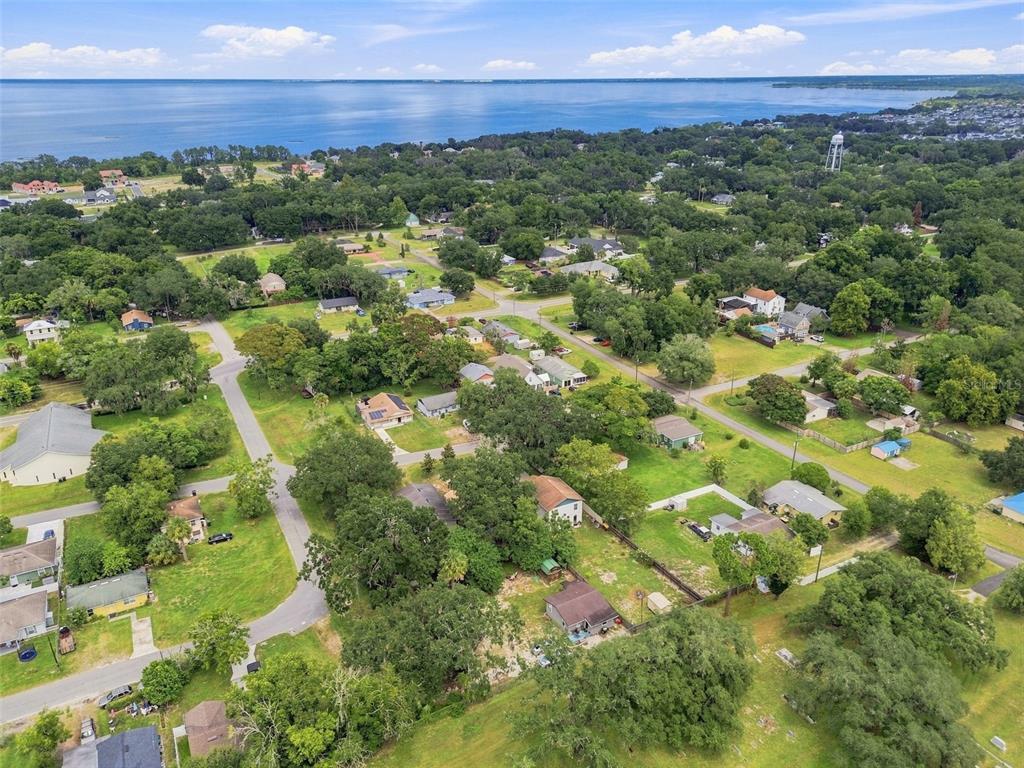 An aerial view shows a residential neighborhood with houses, trees, and a large body of water — 320 W SADLER AVENUE, OAKLAND, FL