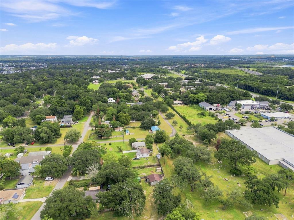 An aerial view shows a residential neighborhood with scattered houses, trees, and a large warehouse — 320 W SADLER AVENUE, OAKLAND, FL