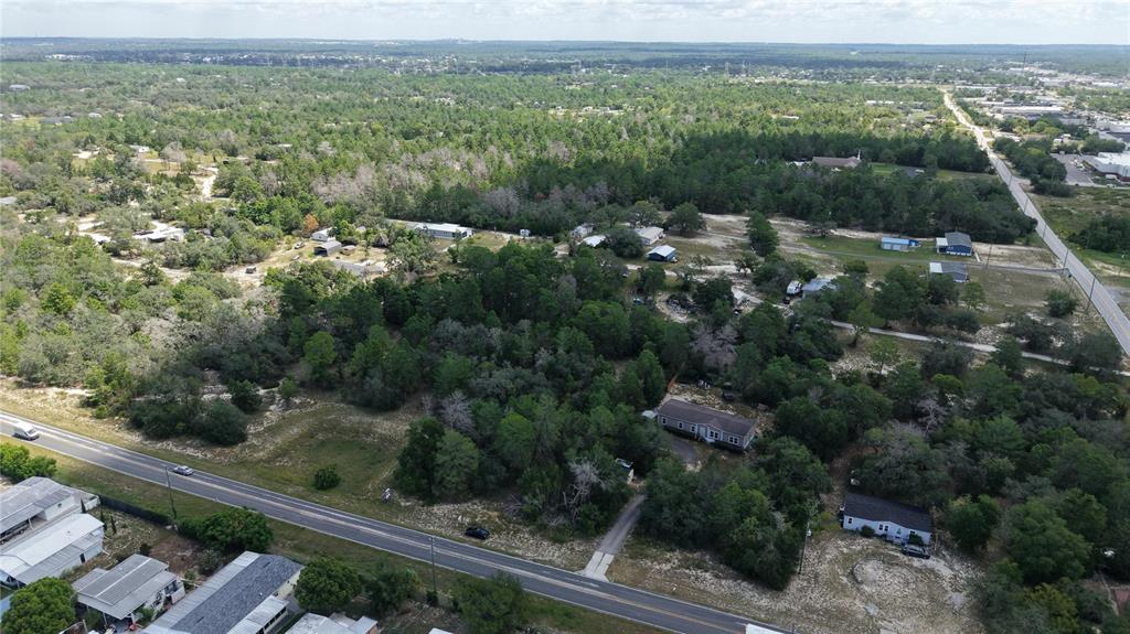 An aerial view shows a rural residential area with scattered houses, trees, and a road — WEEPING WILLOW STREET, BROOKSVILLE, FL