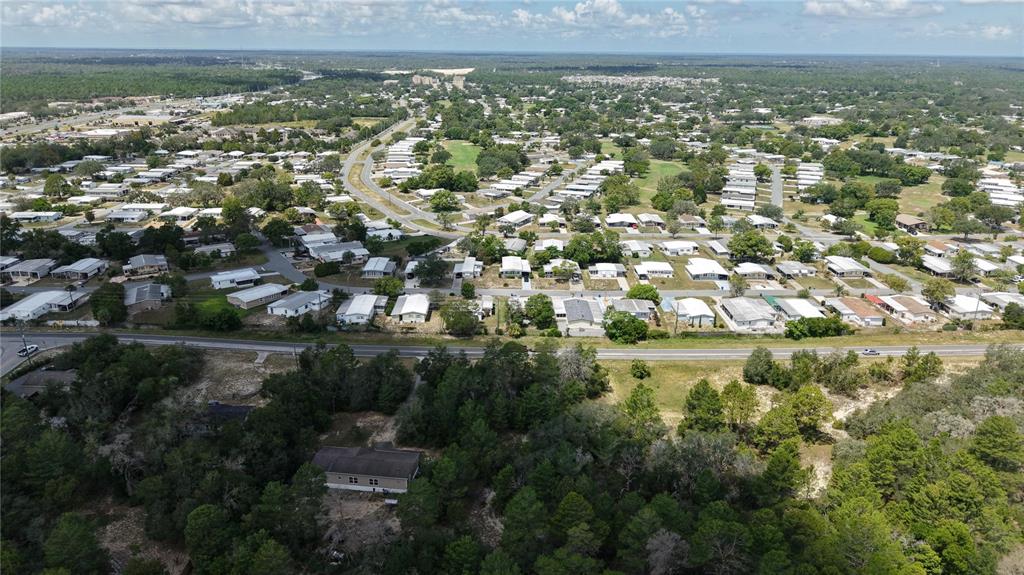 An aerial view shows a residential neighborhood with mobile homes and a wooded area — WEEPING WILLOW STREET, BROOKSVILLE, FL