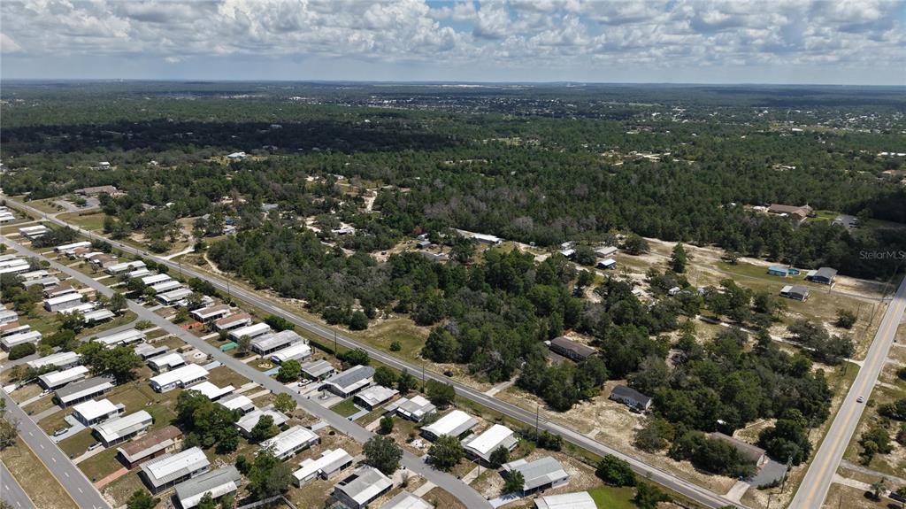 An aerial view shows a residential neighborhood with mobile homes and surrounding wooded land — WEEPING WILLOW STREET, BROOKSVILLE, FL