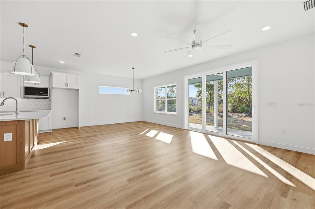 A bright, open-concept living and dining area features light wood flooring and sliding glass doors — 1064 SW 67TH WAY, GAINESVILLE, FL