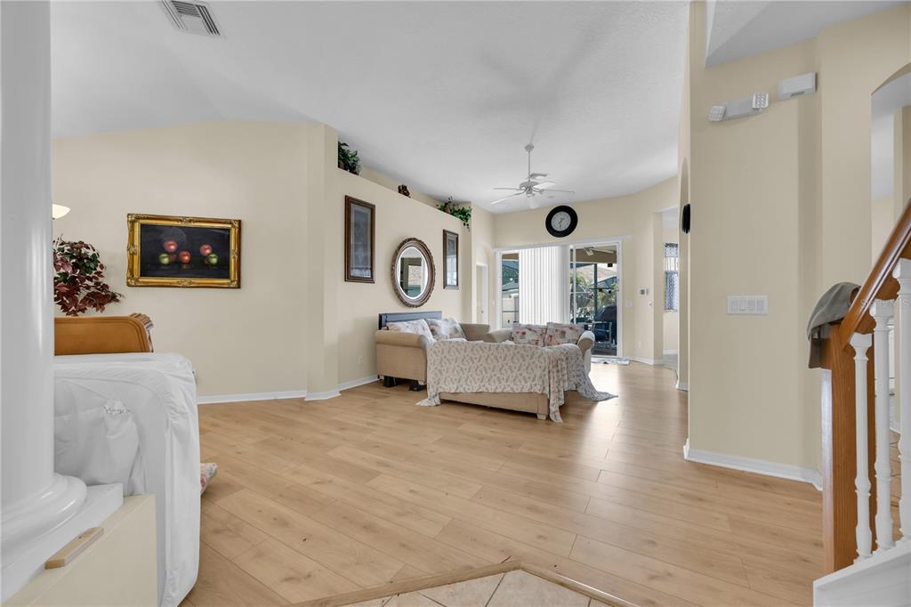 A living room with light wood flooring, a beige sofa, and a vaulted ceiling — 655 MONTARA DRIVE, DAVENPORT, FL