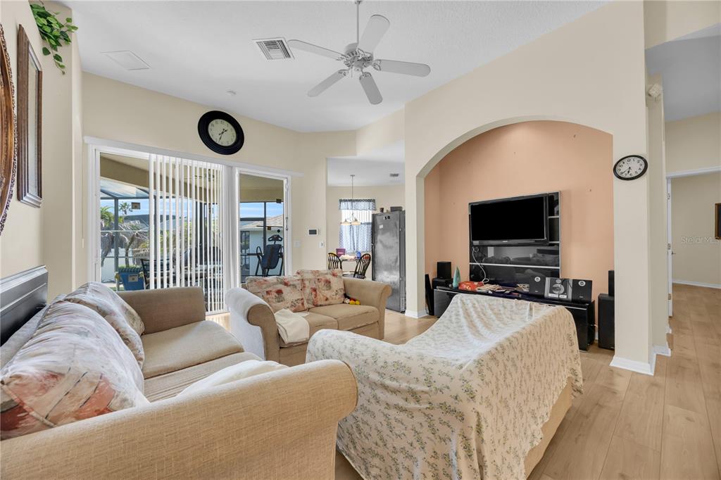A living room features light wood flooring, a ceiling fan, and a television in an alcove — 655 MONTARA DRIVE, DAVENPORT, FL