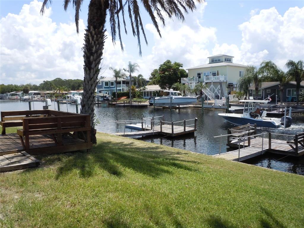 A grassy backyard features a wooden deck, a palm tree, and a private boat dock — 4850 BONITO DRIVE, NEW PORT RICHEY, FL