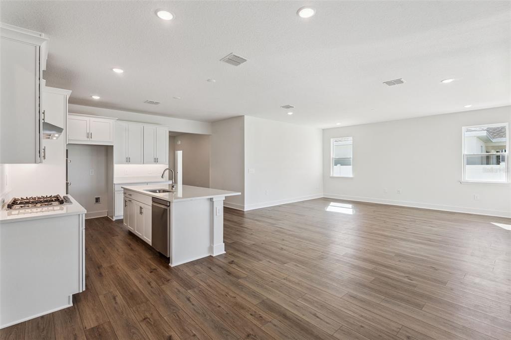 A modern kitchen with white cabinets and an island opens into a spacious living area — 526 EMERALD GROVE DRIVE, APOPKA, FL