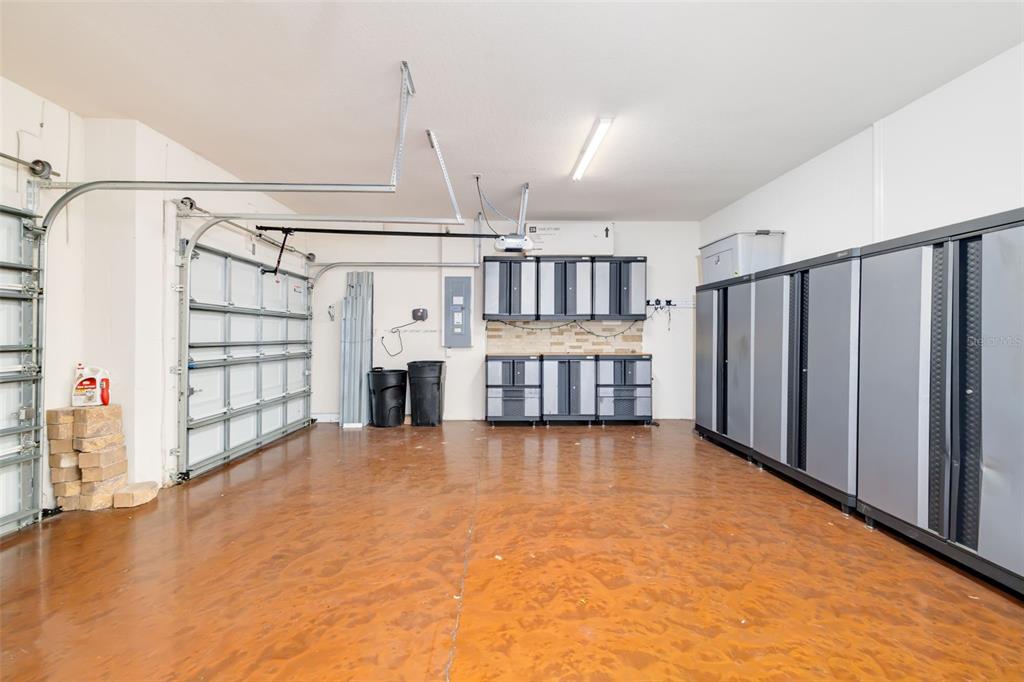 A garage with a stained concrete floor, wall-mounted storage cabinets, and a white sectional door — 7726 111TH TERRACE E, PARRISH, FL