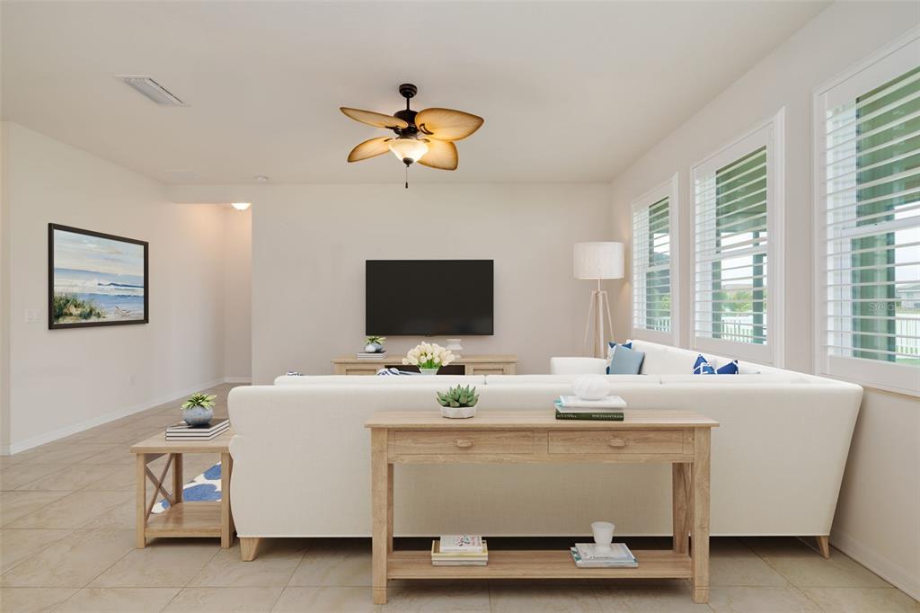 A living room features a white sectional sofa, a wooden console table, and a television — 7726 111TH TERRACE E, PARRISH, FL