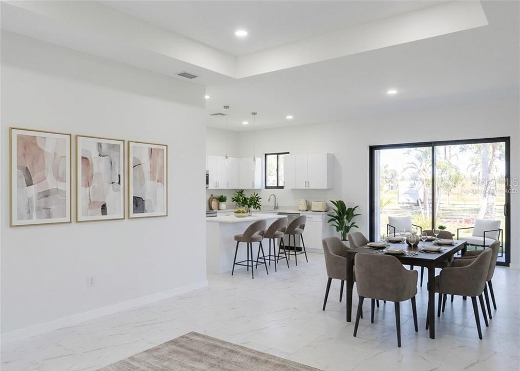 A modern open-concept kitchen and dining area with white cabinets, marble floors, and sliding doors — 1027 KISMET PARKWAY W, CAPE CORAL, FL