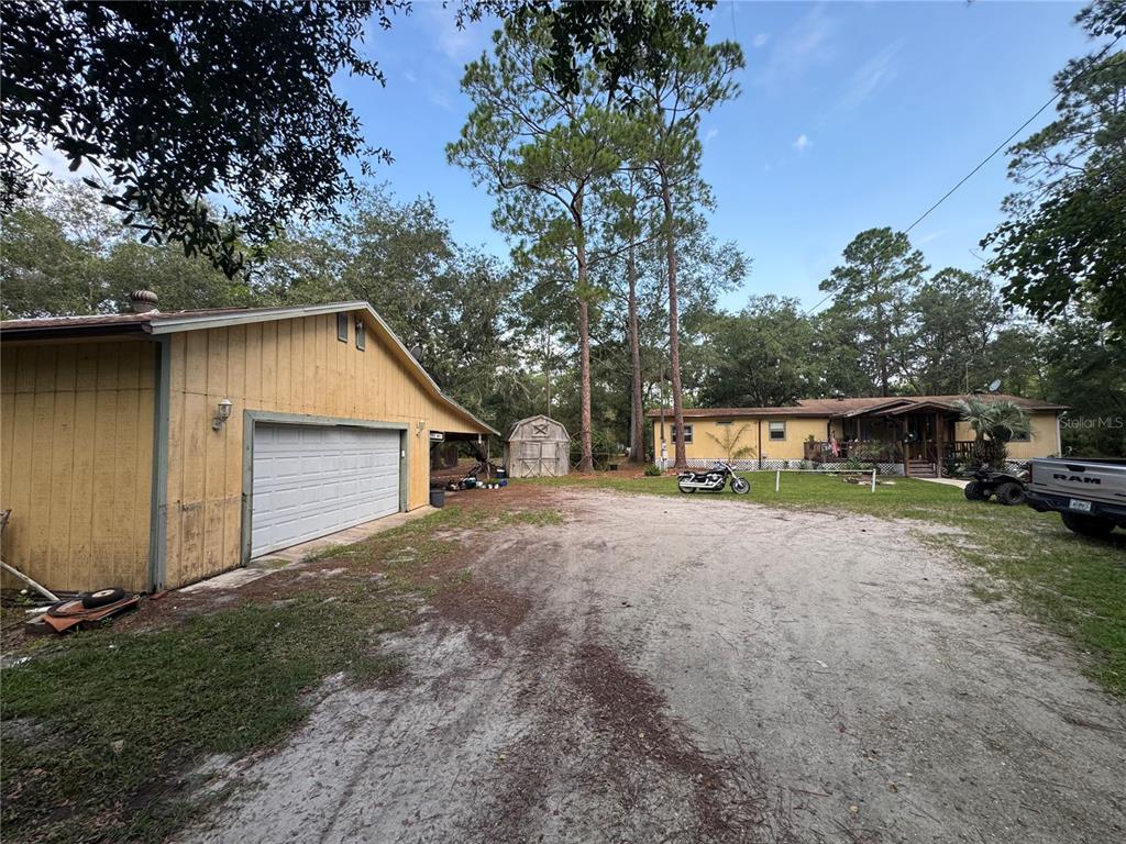 A yellow house and detached garage sit on a large, sandy lot with tall trees — 2790 TOLER AVENUE, DELAND, FL