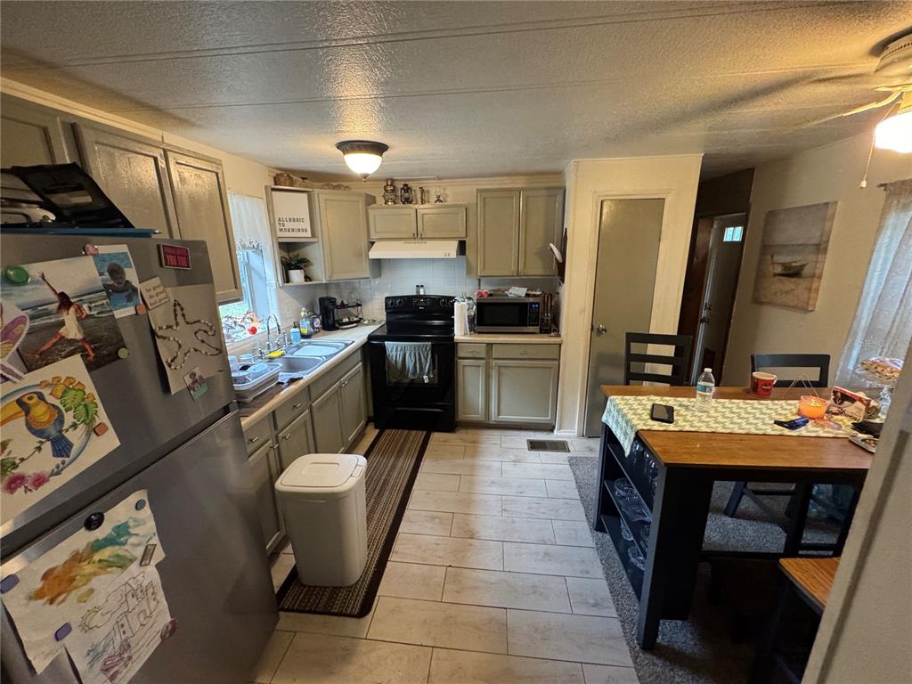 A kitchen with light green cabinets, stainless steel appliances, and a dining table with chairs — 2790 TOLER AVENUE, DELAND, FL